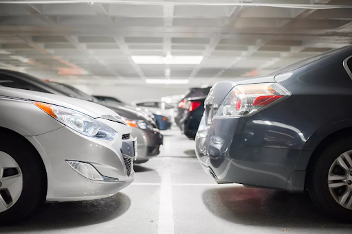 Two lines of parked cars, in a parking garage with a concrete ceiling.